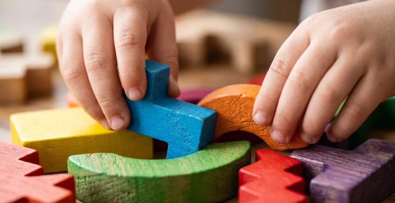 Mains d'enfant manipulant des pièces de puzzle formant des lettres pour l'apprentissage de la lecture