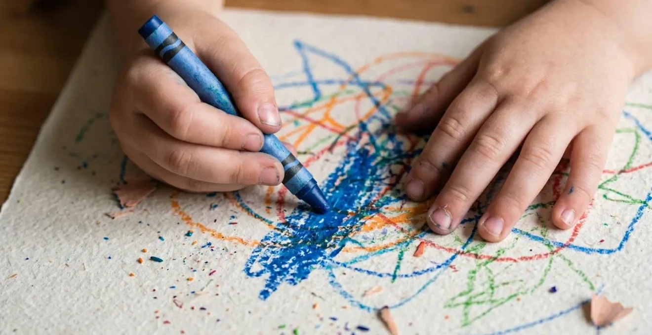 Gros plan sur les mains d'un enfant dessinant avec concentration sur une nappe en papier au restaurant